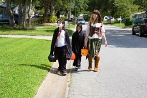 Kids in halloween costumes trick or treating in a suburban neighborhood.