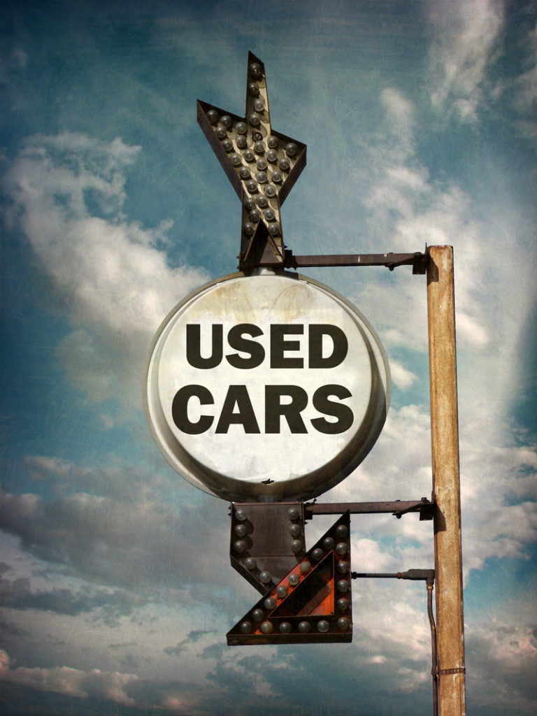 Sign that is worn and says "used cars".