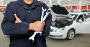 Close-up view of a car maintenance person with a car in the background.