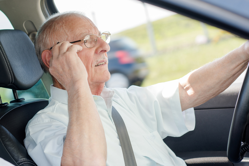 Senior citizen man that is adjusting his glasses as he drives.